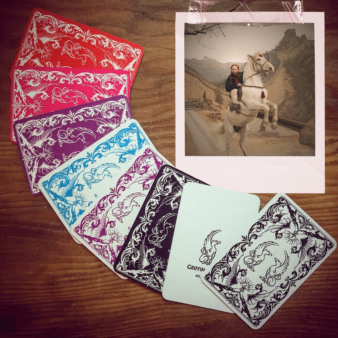 Polaroid photo (of Griffin de Luce on horseback on Great Wall of China)  in upper right corner  Surrounded by an array of name cards in various CMYK colors.